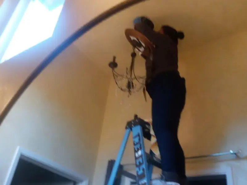 Electrician installing a chandelier in a Bern residence